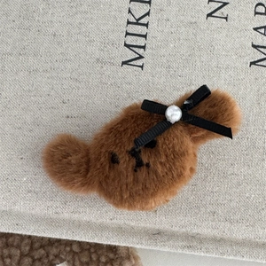 Vista detallada de una pinza para el pelo de oso de peluche con lazo negro y perla