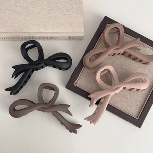 Set of four matte bow hair claws in black, brown, tan, and pink for women