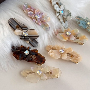Floral acetate hair clips with rhinestones in various colors on white faux fur background