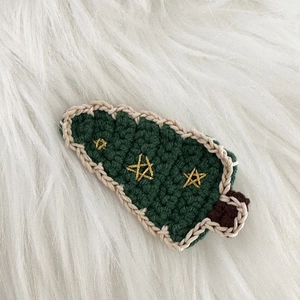 Gros plan détaillé d'une pince à cheveux sapin de Noël au crochet sur peluche blanche