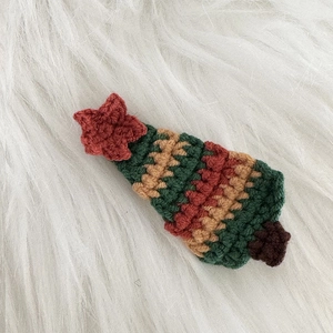 Gros plan détaillé d'une pince à cheveux sapin de Noël au crochet sur un fond en peluche blanche