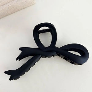 Close-up of a large black matte bow hair claw clip with dense teeth for thick hair