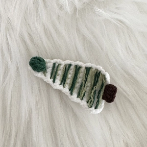 Vue macro détaillée d'une pince à cheveux sapin de Noël tricotée à la main en laine