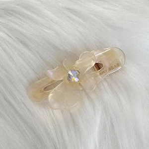 Close-up of champagne flower hair clip with crystal on a soft white plush background