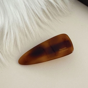 Dettaglio del fermaglio per capelli in tartaruga ambrata con scritta dorata elegante