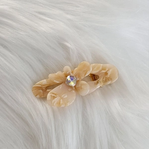 Macro detail of amber marble acetate hair clip with sparkling gemstone and Amy Bear logo
