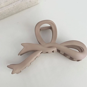 Top view of a matte dusty rose bow hair claw clip for long hair on a white background