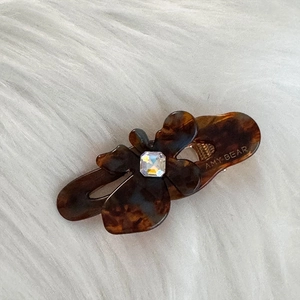 Detailed macro view of acetate flower hair clip with rhinestone and AMY BEAR logo