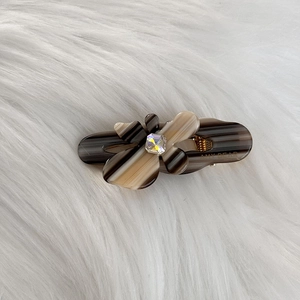 Detail of floral hair clip with amber pattern and crystal centered on soft fur background
