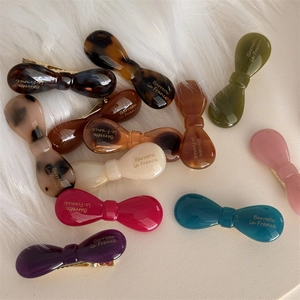 Flat lay of colorful acetic acid bow hair clips with gold Barrette La France lettering