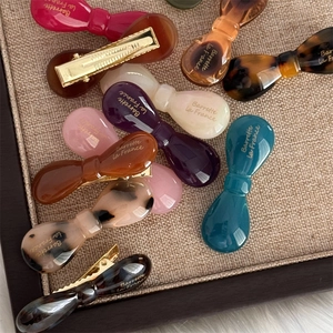 French style acetate bow hair clips in assorted colors on a linen display tray
