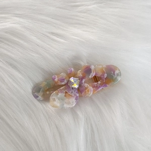 Detail of floral acetate hair clip with marble texture and sparkling center rhinestone