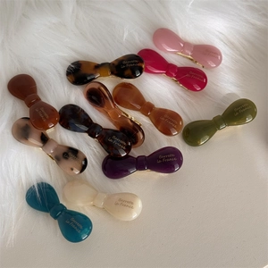 Detail shot of multi-colored acetate bow hair clips with premium glossy finish texture