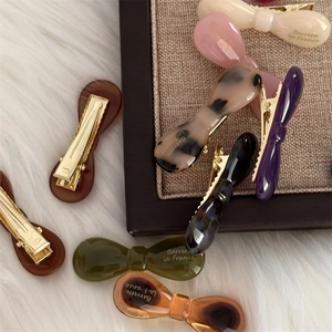 French bow hair clips in assorted acetate colors on a soft white decorative background