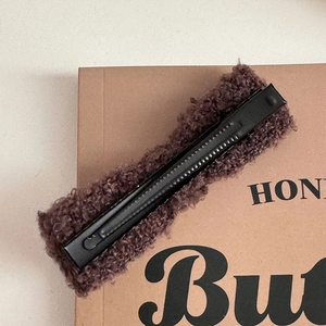Detail view of the brown lamb wool hair clip featuring a black non-slip metal duckbill base