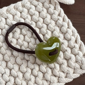Primo piano del cuore in resina verde oliva su elastico per capelli con fondo in maglia