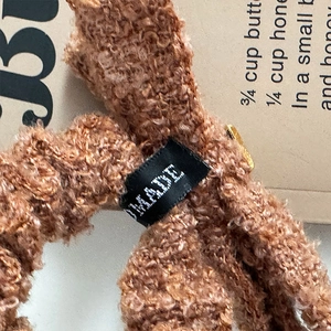 Close-up of caramel brown fleece scrunchie with metallic gold accent and textile label