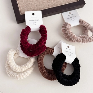 Set of two plush velvet hair scrunchies in various warm autumn colors on a card