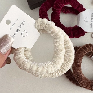 Detailed view of plush elastic hair scrunchies in cream, burgundy and coffee brown tones
