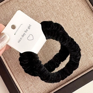 Detail of plush black elastic hair scrunchies with soft chenille texture on display