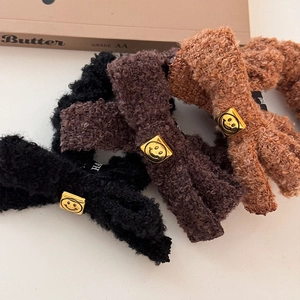 Three plush teddy fleece bow scrunchies in brown and black with golden smiley face plates