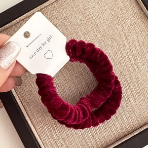 Detail view of two burgundy velvet hair scrunchies with nice day gift tags on a tray