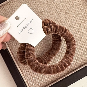 Detail of plush velvet hair scrunchies in brown tones on a decorative gift card