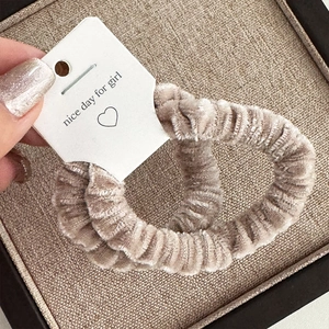Detail view of plush chenille hair scrunchies in soft beige color on display card
