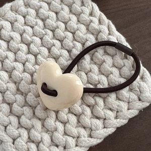 Dettaglio dell'elastico per capelli con cuore in resina color crema e banda marrone