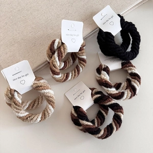 Five thick braided hair ties in warm coffee tones with decorative paper card packaging