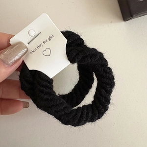 Detail of black thick knitted spiral hair ties set with a white gift card display