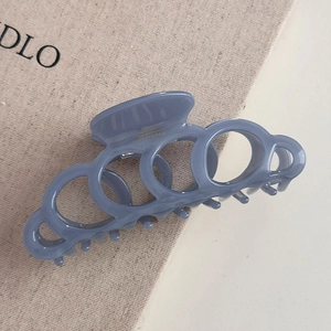 Détail de la pince à cheveux bleue avec anneaux entrelacés et logo imprimé doré