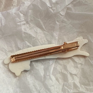 Detail view of the golden metal duckbill hair clip with a cute white cat design