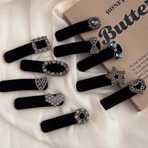 Detail shot of ten diverse black velvet hair clips with crystal rhinestones on a white fabric