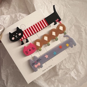Detailed view of three cute cat-shaped hair clips in stripe, plaid, and star patterns