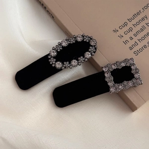 Detailed close-up of retro grey rhinestone hair clips with black flocking on beige fabric