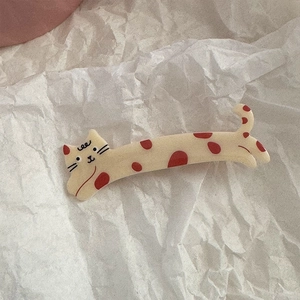 Detail of cream yellow cat hair clip with red dots on a stylish crinkled paper background