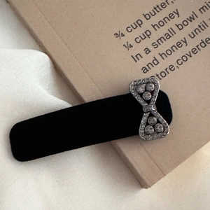 Close-up of black flocked hair clip with silver rhinestone bow on craft paper