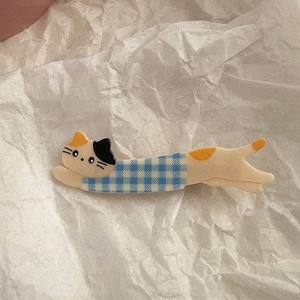 Detail shot of a cute long calico cat hair clip in blue checkered shirt on white paper