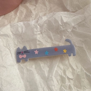 Close-up of cute grey cat hair clip with colorful star patterns and pink bow details
