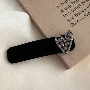 Detail of vintage black velvet hair clip with a sparkling rhinestone heart decoration