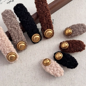 Close-up of fuzzy lamb wool hair clips with elegant vintage gold buttons in earth tones