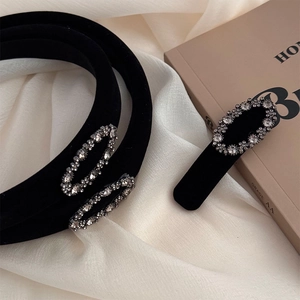 Elegant black velvet headband with oval rhinestones on silk fabric and book background