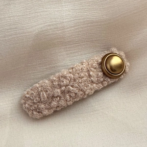Close-up of retro beige sherpa fleece hair clip with a vintage matte gold metal button