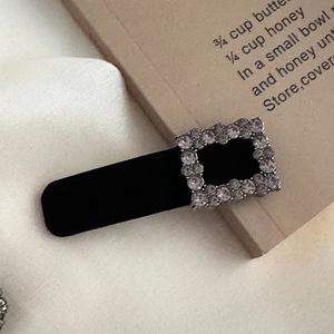 Detailed macro view of a vintage black velvet hair clip with square rhinestones