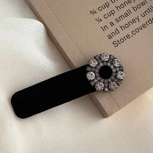 Detail of vintage black velvet hair clip with sparkling rhinestone circular metal accent