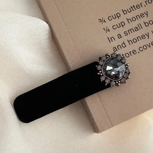 Detailed close-up of retro black velvet hair clip with a grey rhinestone gemstone