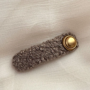 Macro view of brown lamb wool hair clip texture with vintage gold metal button detail