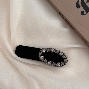 Detail of elegant black velvet headband with sparkling oval crystal floral decorations