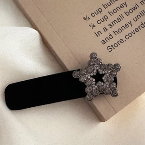 Detail of a vintage star hair clip with grey rhinestones on black velvet fabric